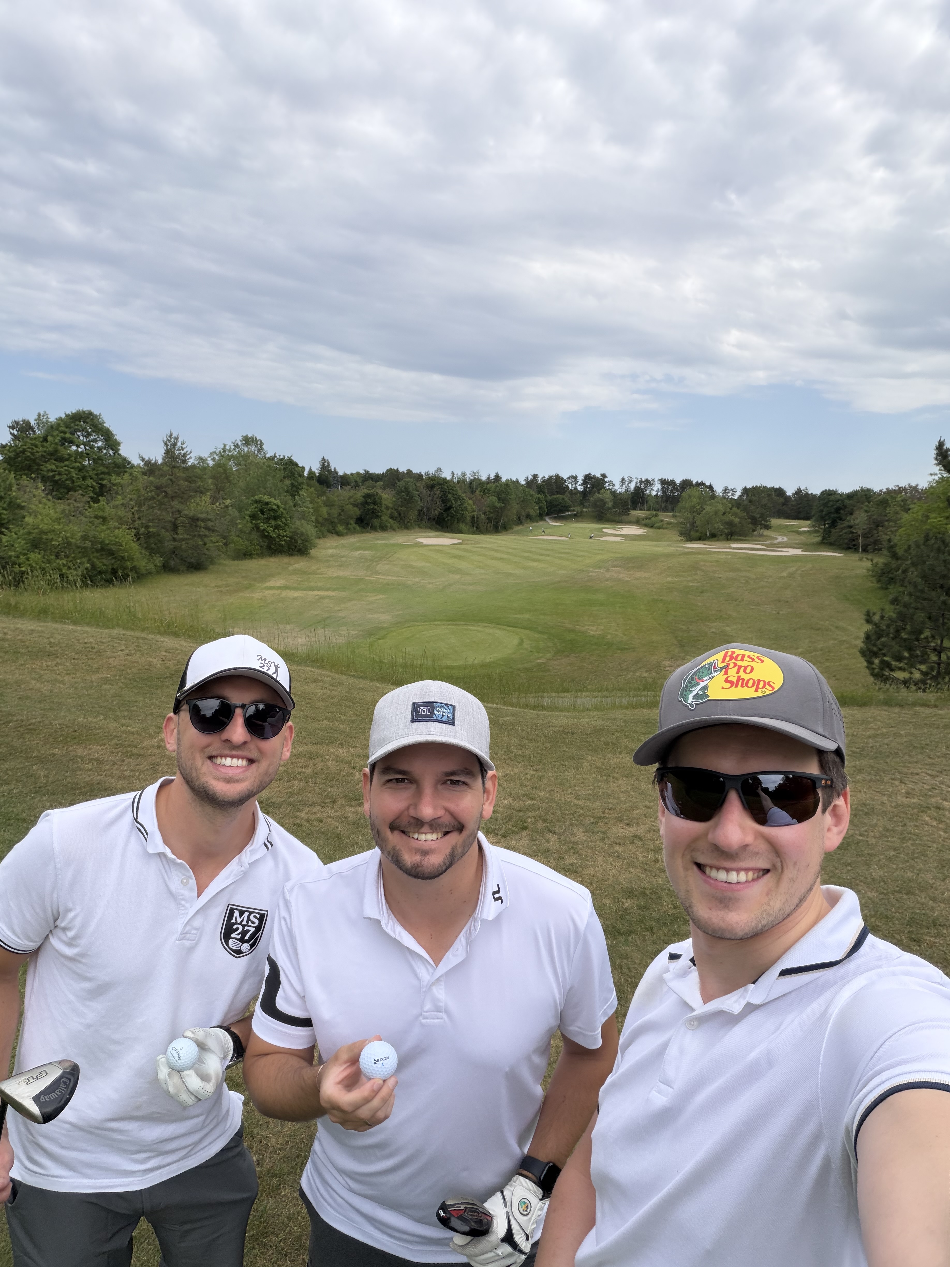 Drei Golfer posieren lächelnd am Abschlag